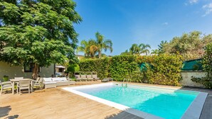 A rectangular swimming pool with a wooden deck and lounge chairs. - Vanilla Bay Dep Apartment with Private Pool, Private Garden, and Air Conditioning (San Giovanni La Punta)