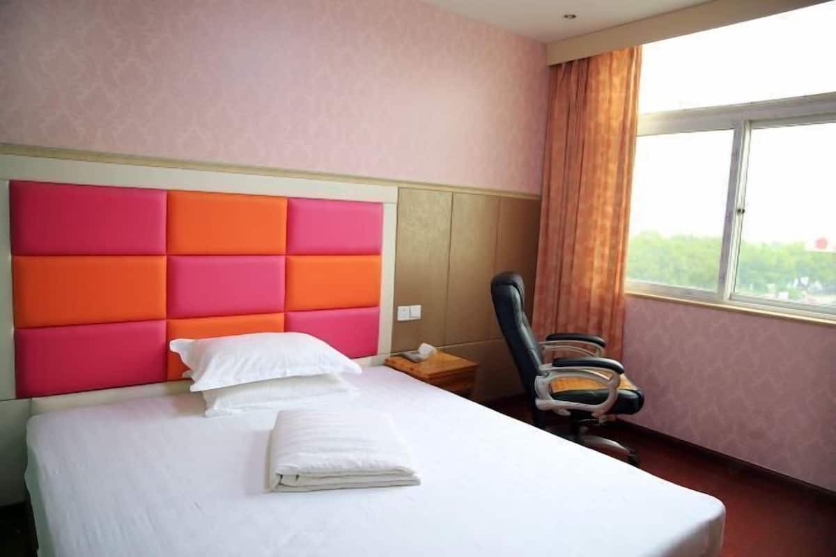 A hotel room with a bed, a chair, and a window with curtains.