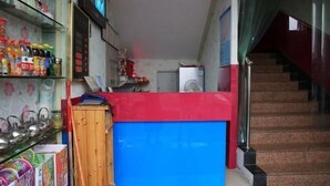 Un couloir étroit avec un comptoir bleu, un meuble en bois et un escalier menant à un niveau supérieur.