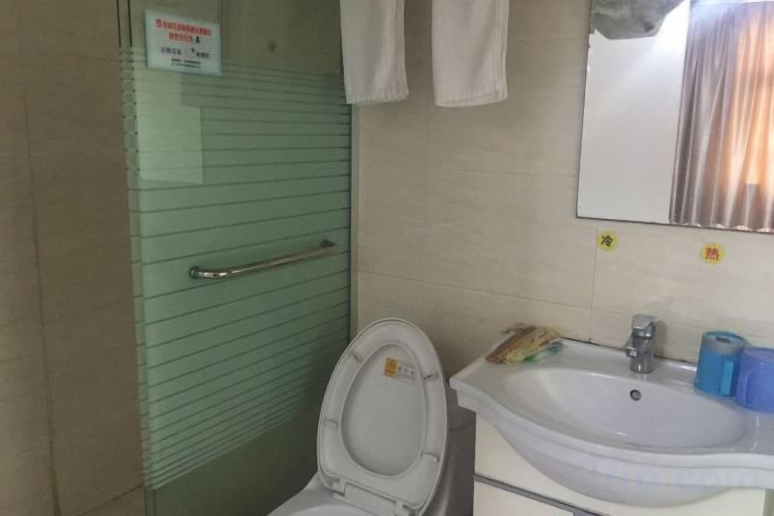 A bathroom with a glass partition, a white sink, and a mirror.