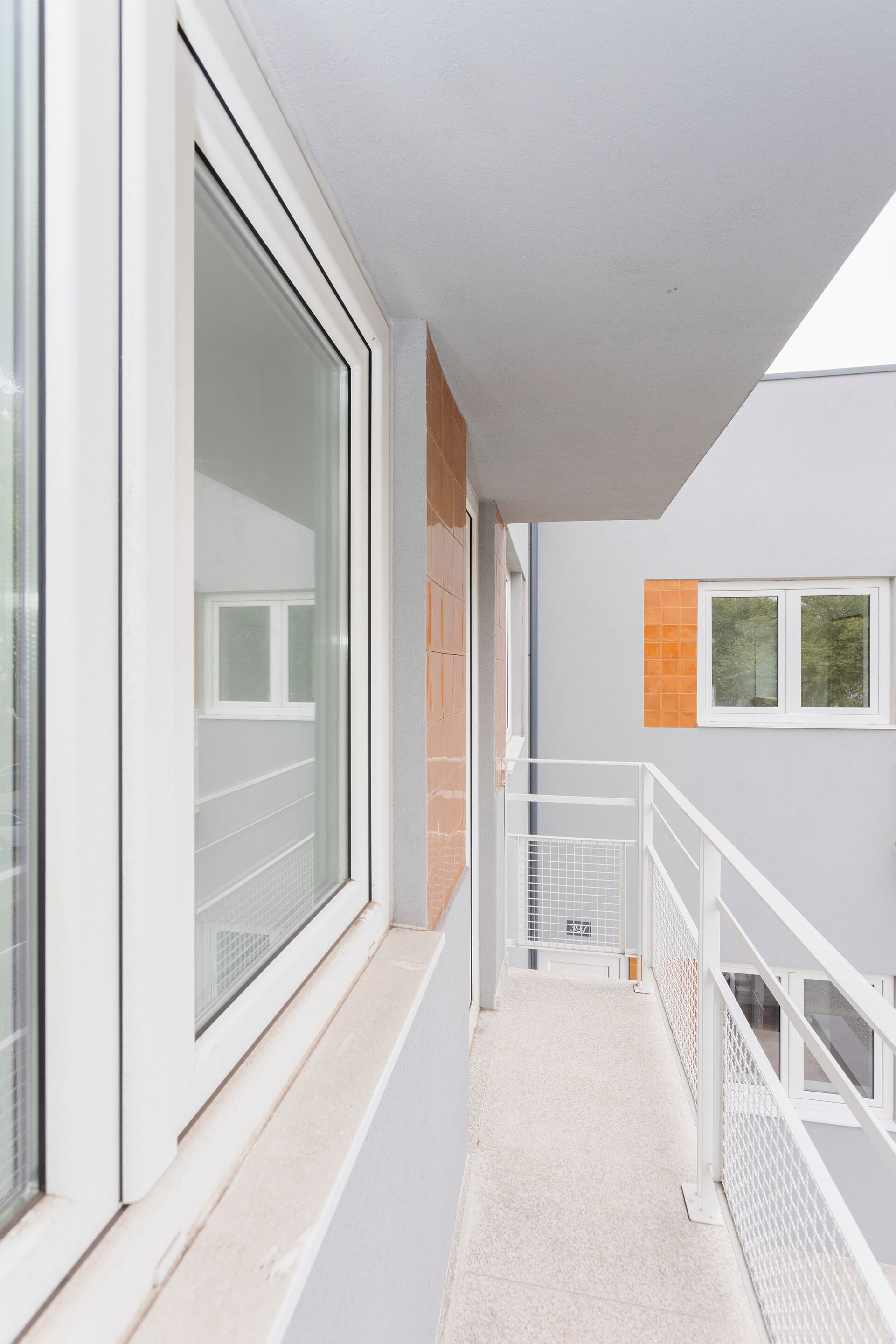 A narrow corridor with a window on the left and a door at the end.