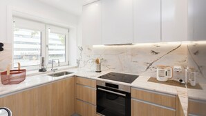 A modern kitchen with a marble backsplash, stainless steel appliances, and wooden cabinets. - Colorwave Terrace House (Matosinhos)