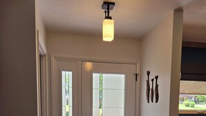 En hall med en dubbeldörr, en lampa och en utsikt genom dörren.