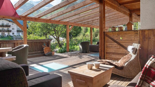 A wooden deck with outdoor seating, a pool, and a view of a mountain.