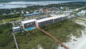 A coastal hotel with a long building, a swimming pool, and a beach access bridge. - Beacher's Lodge 307 by Distinctive Beach Rentals (St. Augustine)