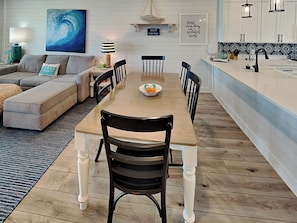 Un coin repas avec une table et des chaises en bois, un canapé et, au fond, une cuisine.