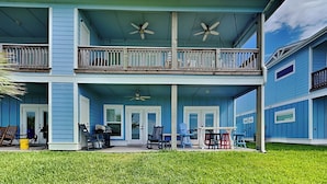 A two-story building with a balcony, a covered patio, and a small outdoor seating area. - Copano Coastal Gem by Miss Kitty’s (Rockport)