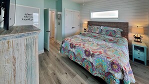 A bedroom with a bed, a ceiling fan, a TV, and a dresser. - Copano Coastal Gem by Miss Kitty’s (Rockport)
