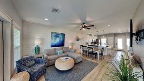 A spacious living area with a sofa, a dining table, and a kitchen in the background. - Copano Coastal Gem by Miss Kitty’s (Rockport)