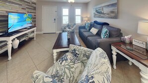 A living room with a television, sofa, coffee table, and decorative items. - Kontiki Beach Resort #317 by Miss Kitty’s (Rockport)