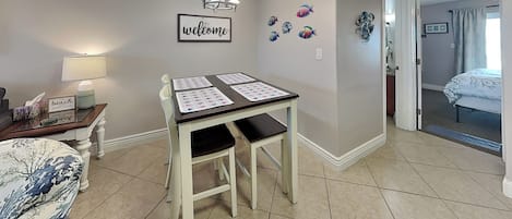 A room with a table set up for a meeting, a 'welcome' sign on the wall, and a bed in the background.