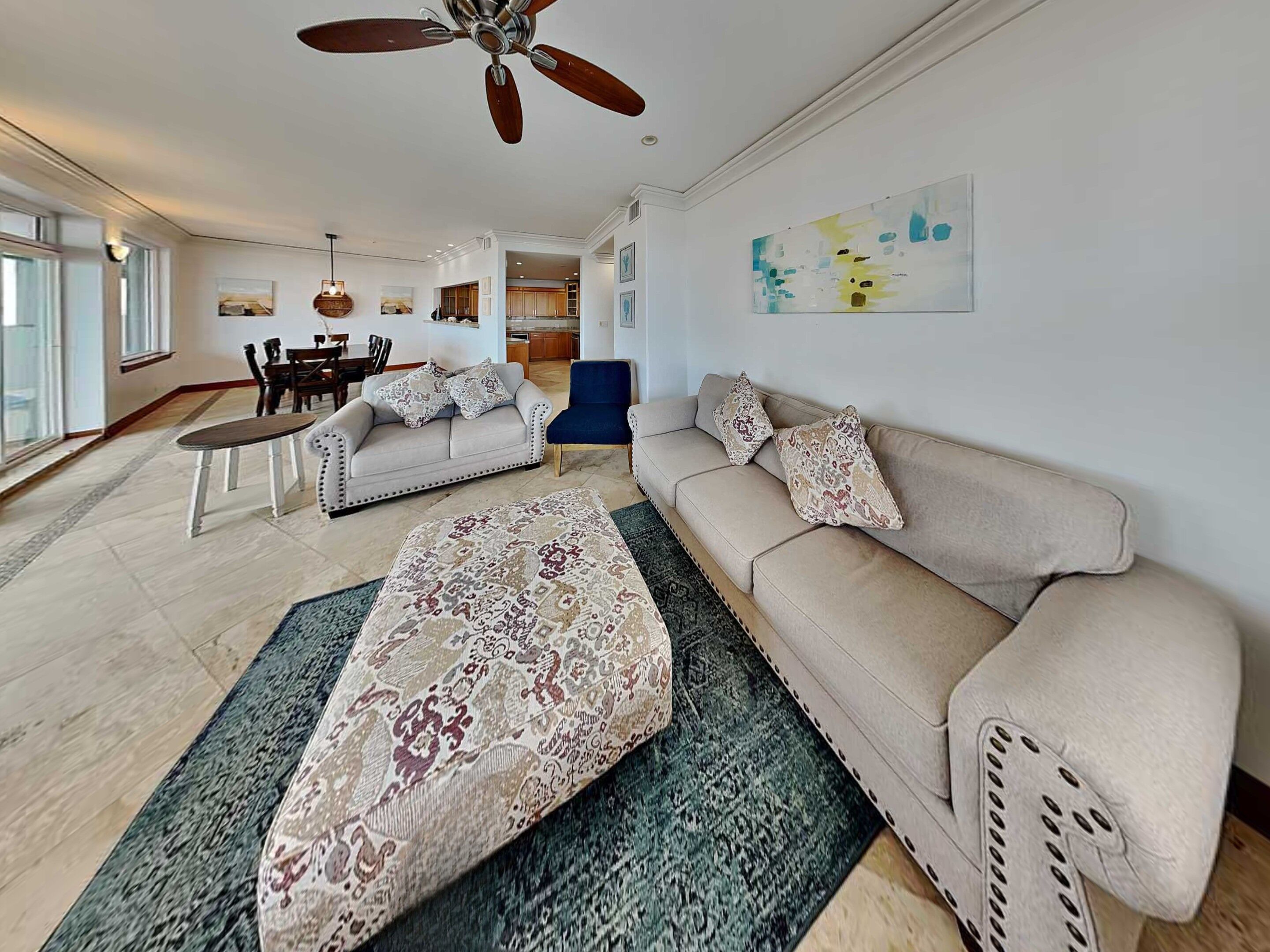 A spacious living room with a sofa, ottoman, and dining area.