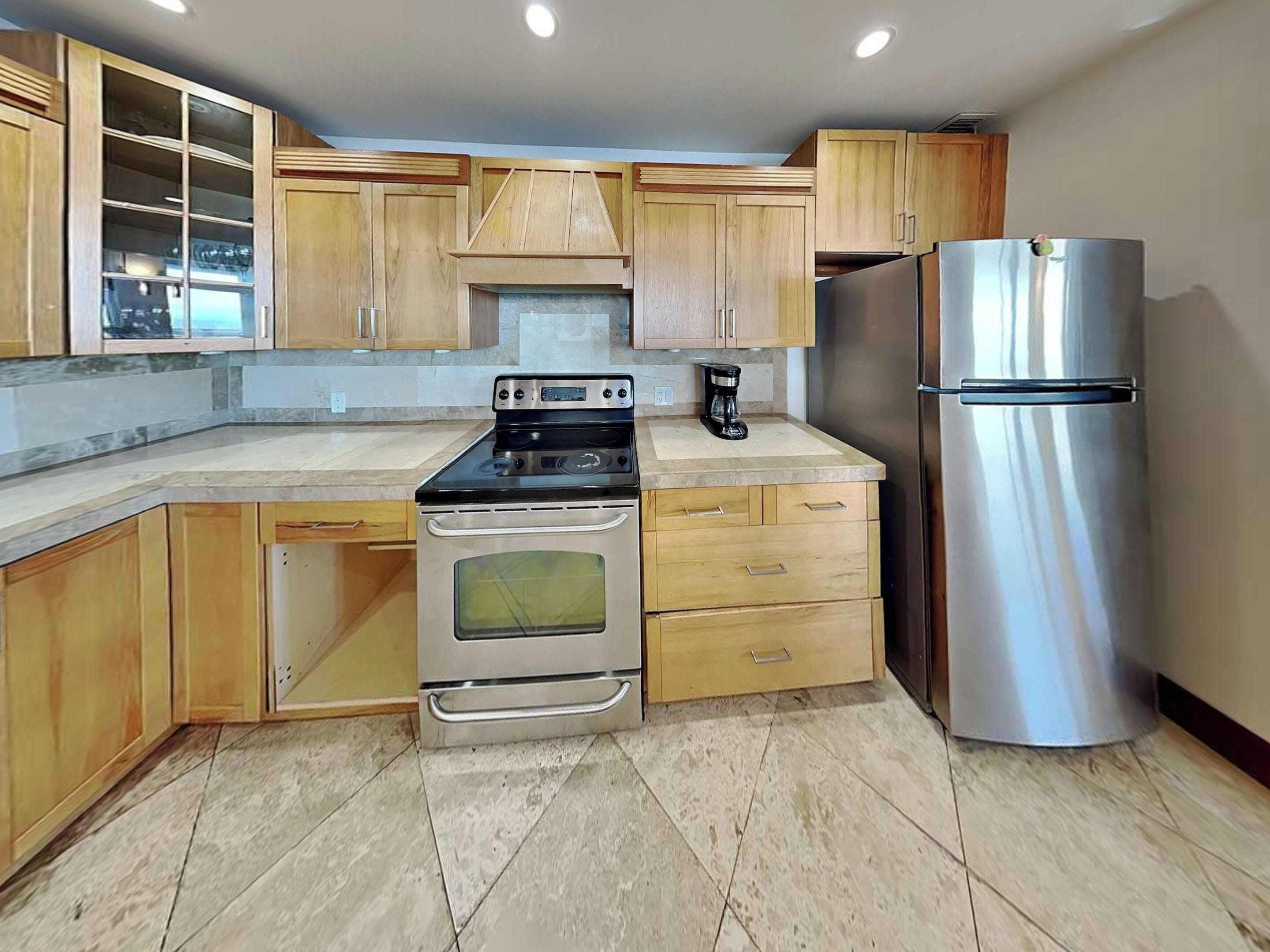 A kitchen with wooden cabinets, a stainless steel refrigerator, a built-in oven, and a coffee maker.