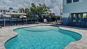 A swimming pool with a curved edge, surrounded by a stone deck.