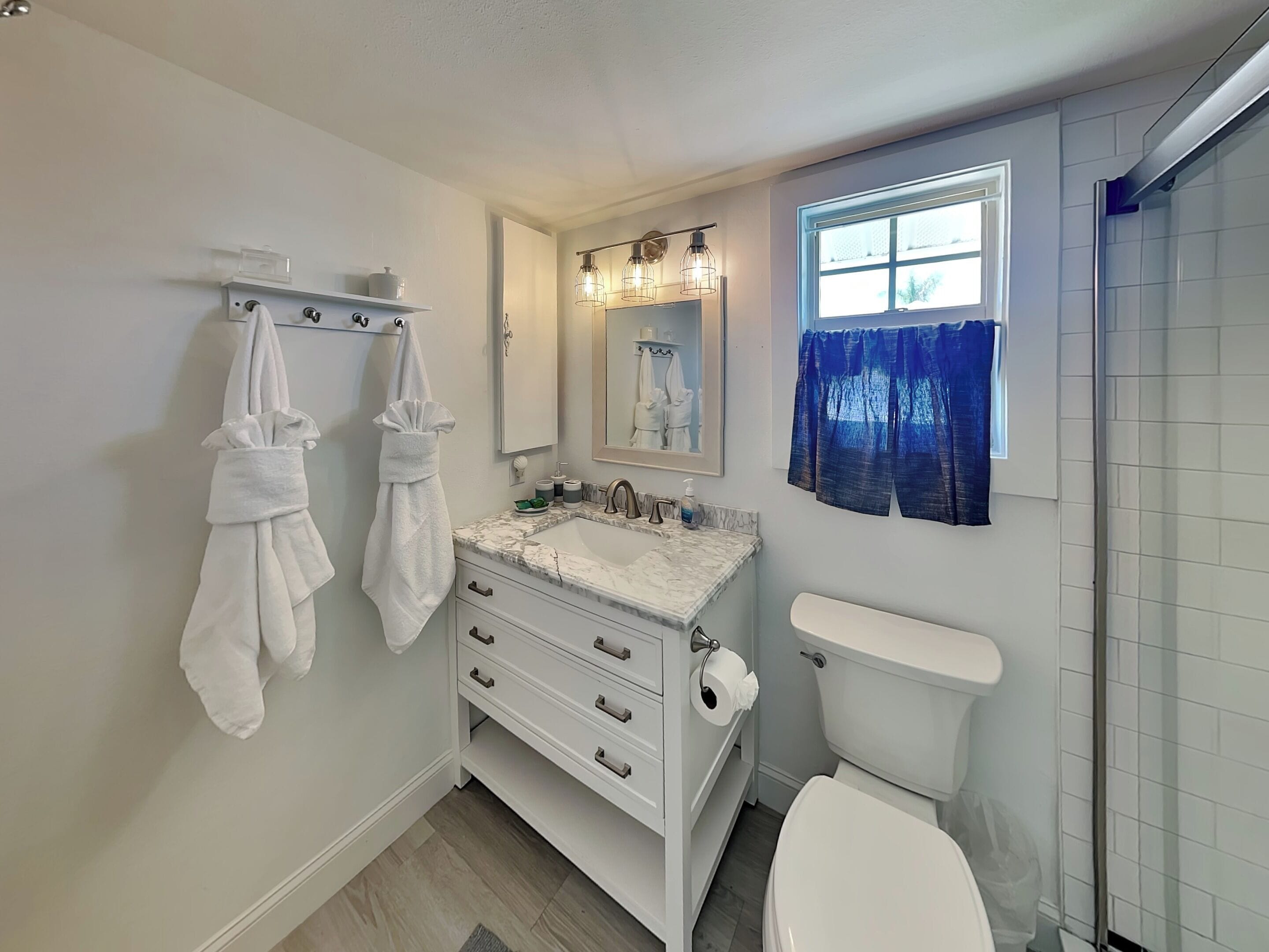 A modern bathroom with a white vanity, a toilet, and a shower area.