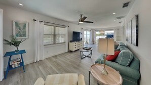 A modern living room with a sofa, a coffee table, a TV, and a ceiling fan.