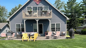 A two-story house with a balcony, outdoor seating area, and a well-maintained lawn.