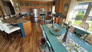 A kitchen with wooden cabinets, a stainless steel refrigerator, and a dining area with a table and chairs.