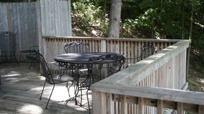Puinen terassi, jossa on pyöreä pöytä ja tuoleja, ja terassin ympärillä on puinen aita.