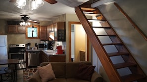 A kitchen with wooden cabinets, a microwave, a stove, and a sink. There is a wooden staircase leading to another room. - Lake Escape #2 in Hocking Hills (Logan)