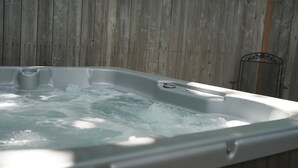 A hot tub with water, set against a wooden wall.