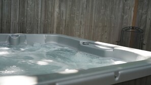 A hot tub with water, set against a wooden wall.