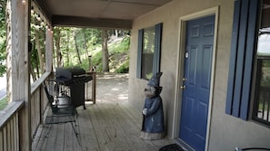 A covered porch with a grill, a statue, and a blue door. - Lake Escape #2 in Hocking Hills (Logan)