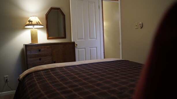 A bedroom with a bed, a dresser, a mirror, and a lamp.