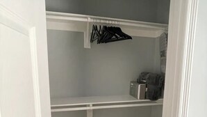 Un armario vestidor con paredes grises, estantes blancos y piso de baldosas.