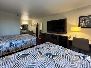 A hotel room with two beds, a TV, a desk with a lamp, a chair, and a bathroom visible in the background. - Studio 6 Suites Santa Ana, Ca (Santa Ana)