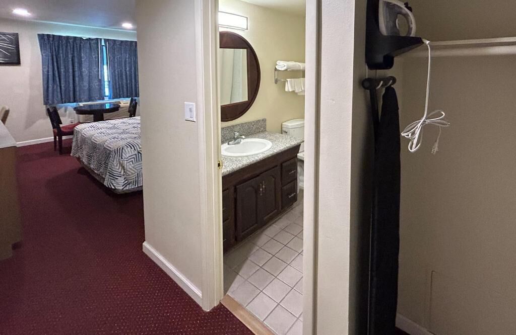 Habitación de hotel con cama, baño con lavabo y espejo, y escritorio con silla.