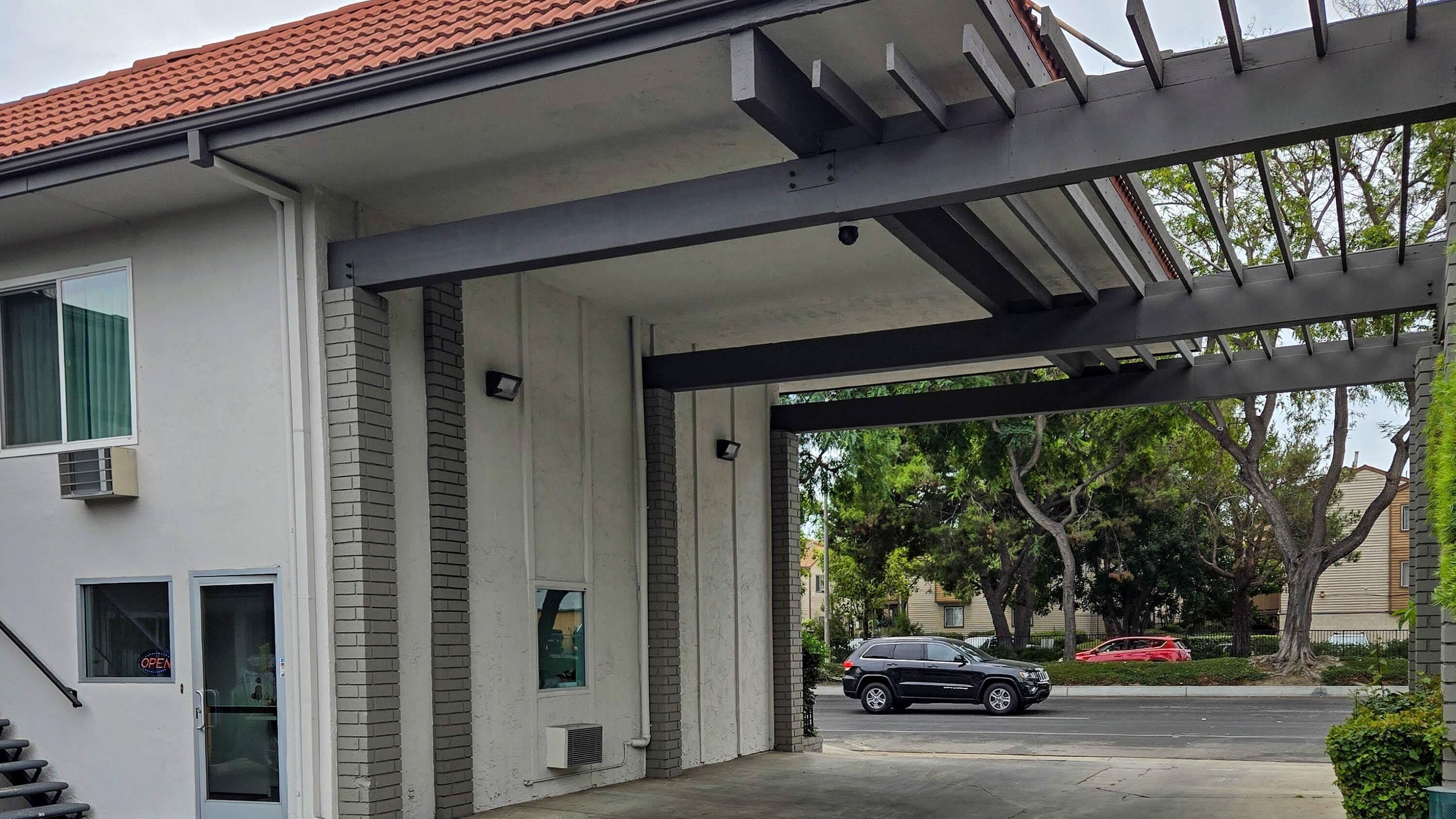 A modern building with a covered entrance, a brick facade, and a car parked in the driveway.