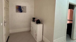 A hallway with a white cabinet, a painting on the wall, and a door on the left. - marrakesh apartment (Marrakech)
