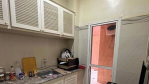 A compact kitchen with white cabinets, a granite countertop, and a black stove. - marrakesh apartment (Marrakech)