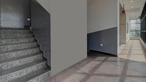 A modern interior with a staircase, a hallway, and a view of a tower. - Hotel Light House Comforts - Mysore (Mysore)