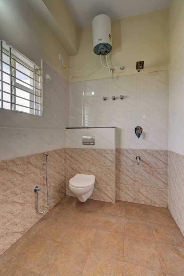A bathroom with a toilet, a shower, and a water heater. - Hotel Light House Comforts - Mysore (Mysore)