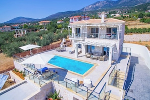 Eine zweistöckige Villa mit Swimmingpool, Außenbereich und Blick auf die umliegende Landschaft.