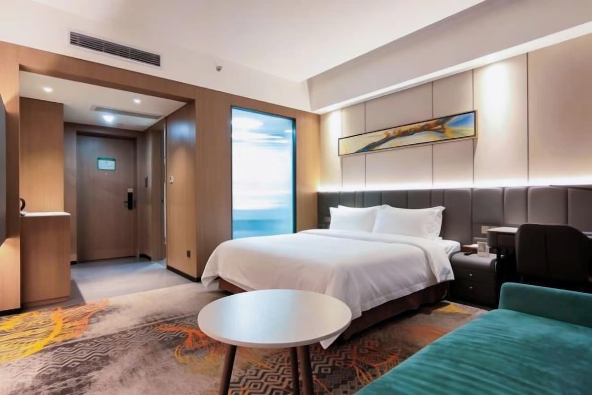 Quarto de hotel com cama, mesa redonda, sofá e um quadro na parede.
