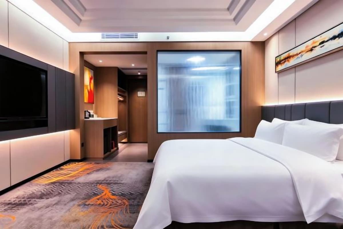 Quarto de hotel com cama, televisão, banheiro e vista para uma cascata.