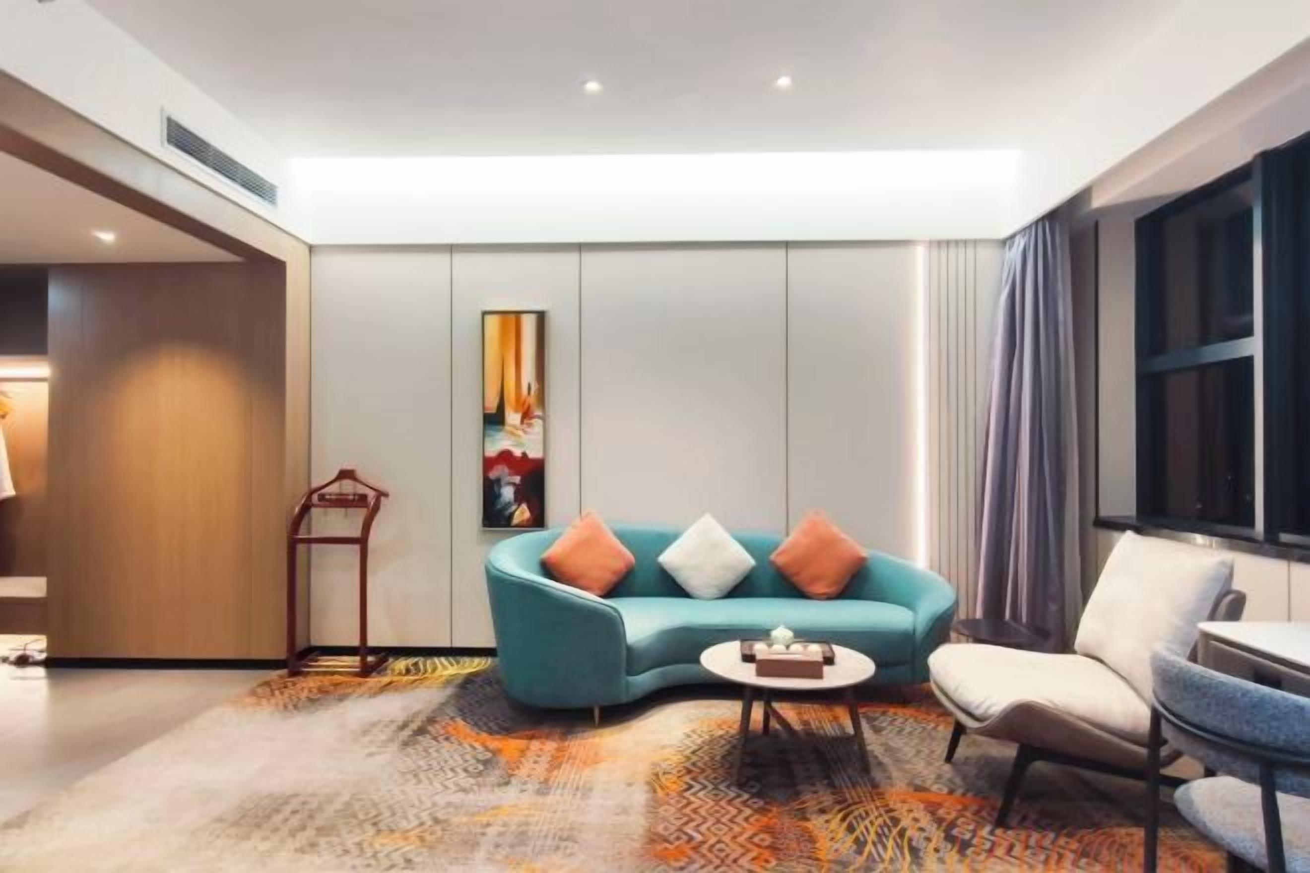 A modern living room with a teal sofa, a small round coffee table, and a beige armchair.