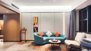 A modern living room with a teal sofa, a small round coffee table, and a beige armchair.