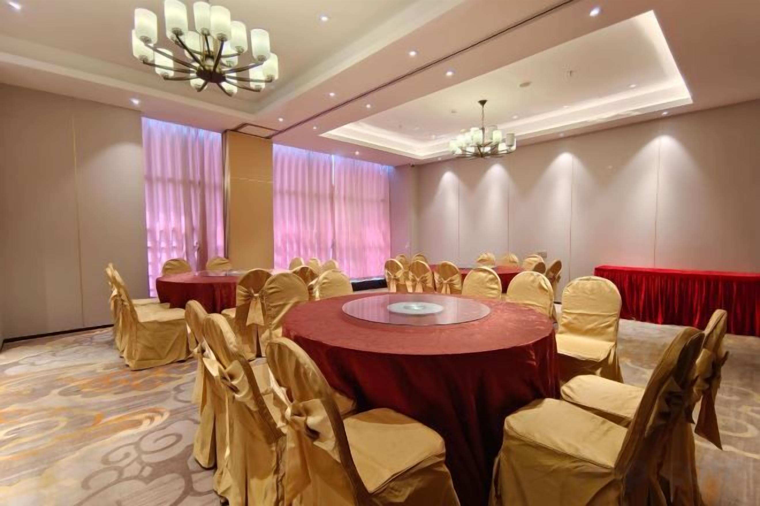 A conference room with round tables, chairs, and a chandelier.