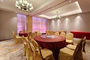 Un salón de conferencias con mesas redondas, sillas y una araña.