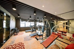 Ett gym med löpband, styrketräningsmaskiner och träningsbänkar.