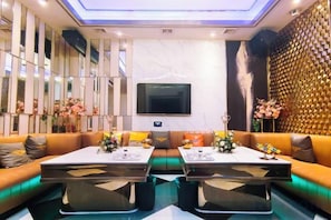 A modern living room with a sofa set, a flat-screen TV, and a decorative wall.