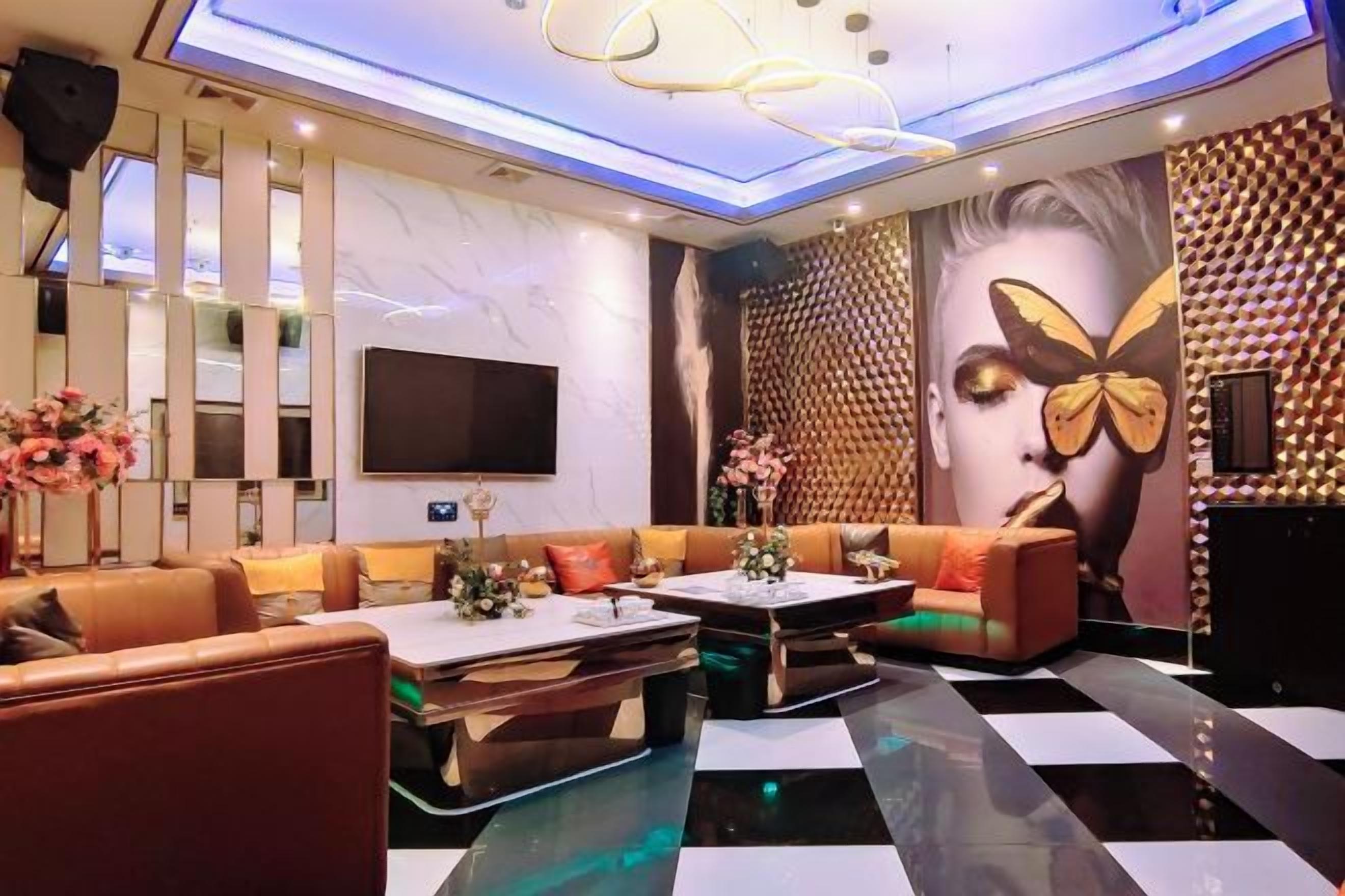A modern lounge area with leather sofas, a flat-screen TV, and a patterned wall.