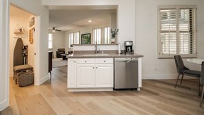 Een moderne keuken met witte kasten, een vaatwasser en een eethoek met een tafel en stoelen.