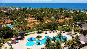 Un resort con varias piscinas, palmeras y vista al mar.