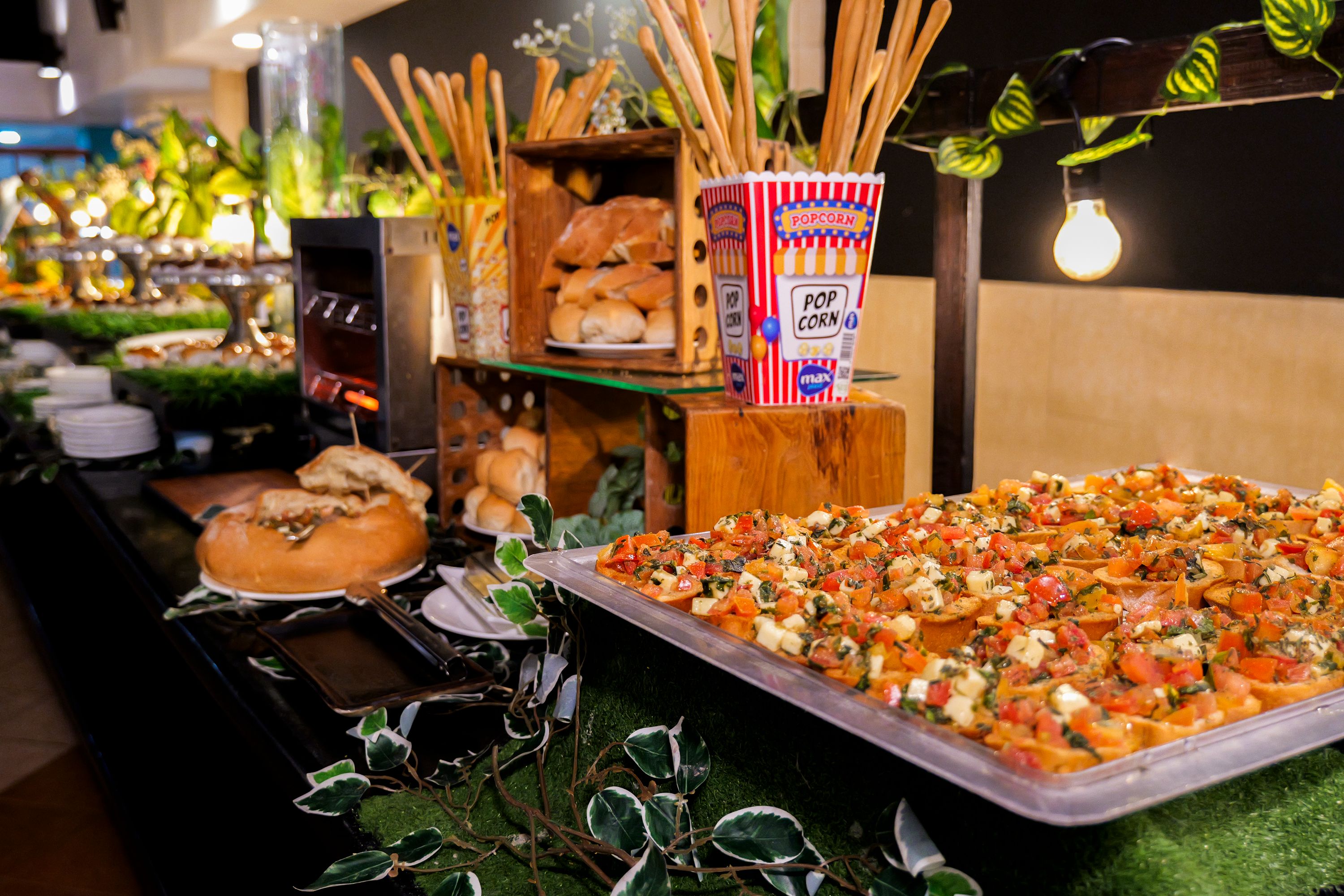 Un bufé con diversos alimentos, incluyendo una bandeja de aperitivos, pan y un recipiente con palomitas.