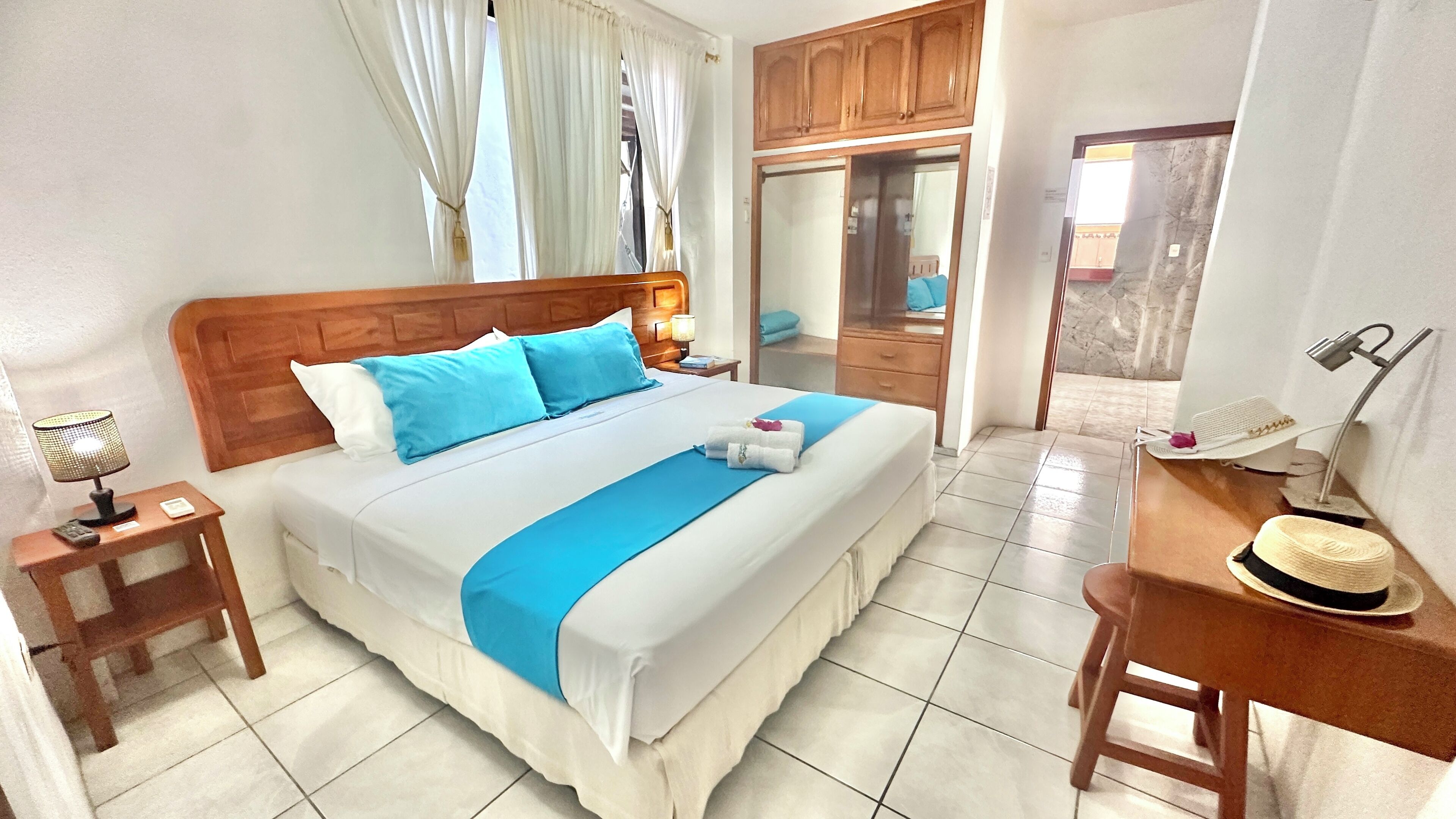 A neatly arranged hotel room with a bed, bedside tables, a desk, and a mirror.